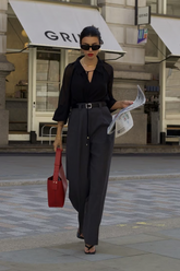 a lady in a black bow tie neck shirt and a pair of grey pants